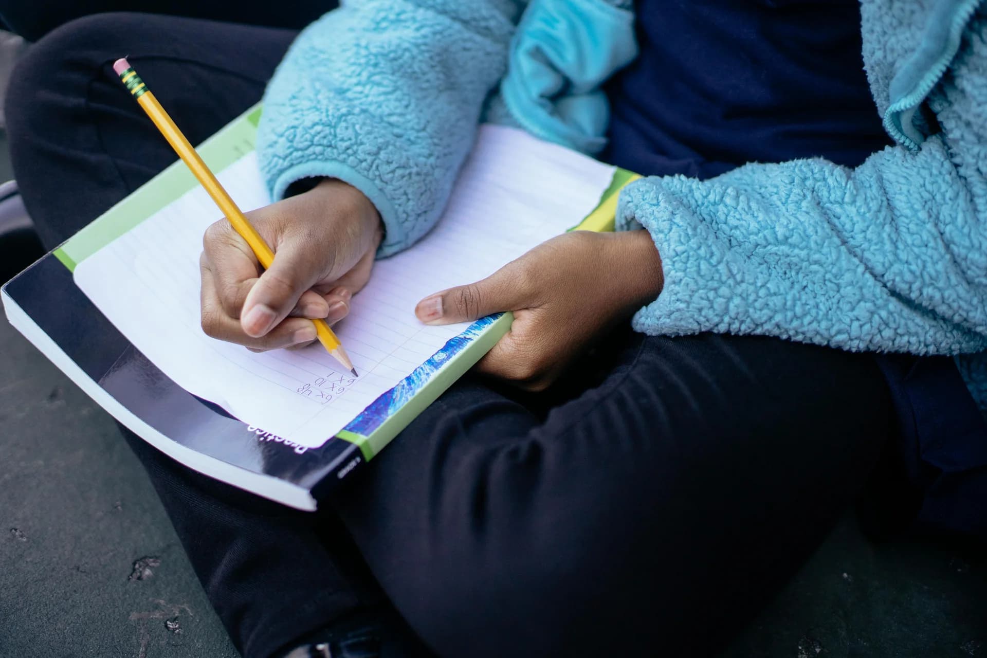 Mains d'un enfant qui écrit au crayon dans un cahier